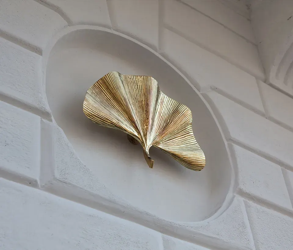 A golden ginkgo leaf, the hotel's emblem, set in an oval relief on a white stone wall.